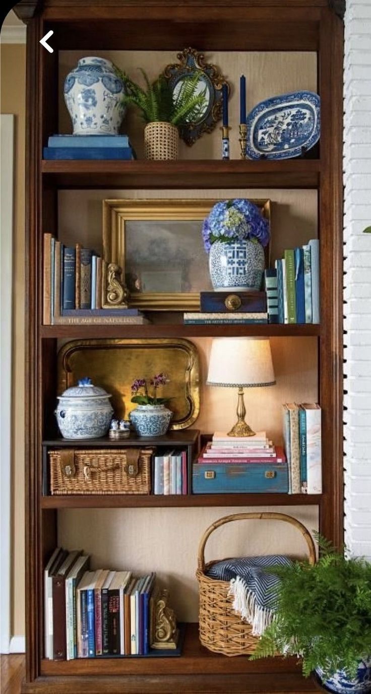 a bookshelf filled with blue and white vases