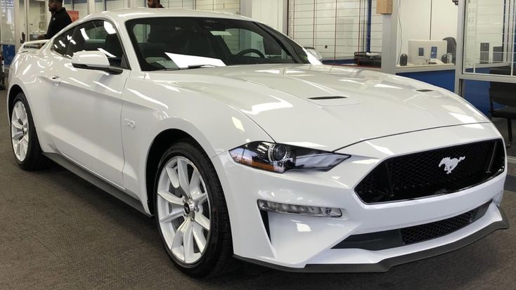 a white mustang car is parked in a showroom