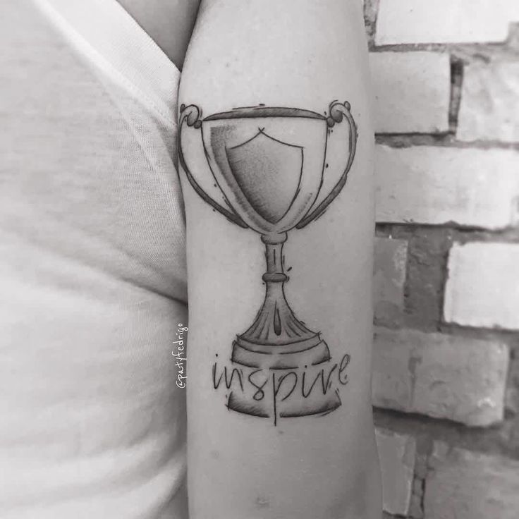 a person with a tattoo on their arm holding a trophy