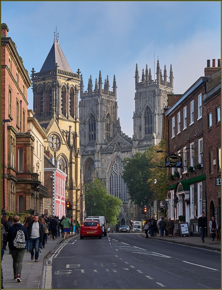 people are walking down the street in front of some old buildings and tall cathedrals