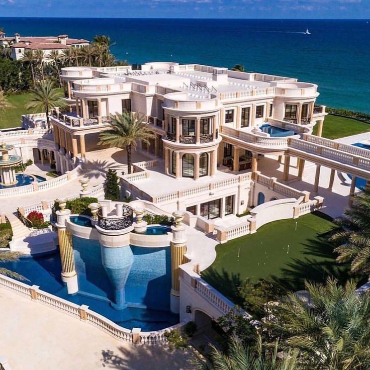 this is an aerial view of a mansion on the beach in palm trees and blue water