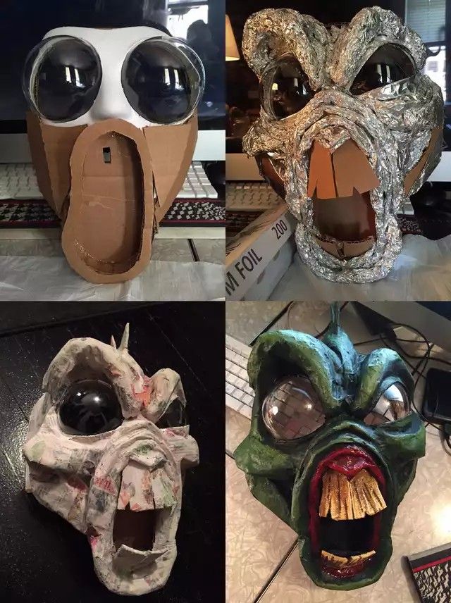 four different masks made out of cardboard and paper machs, each with an open mouth