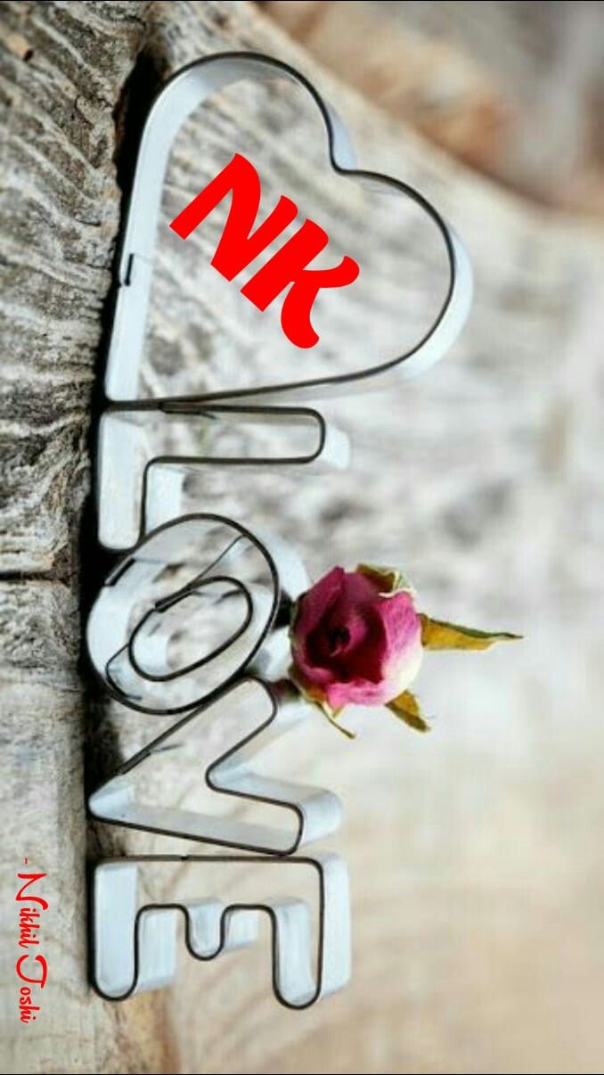 a pink rose sitting on top of a piece of wood with the word love spelled in red