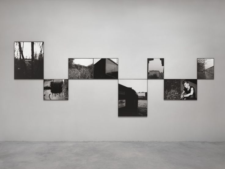 black and white photographs hanging on the wall in an empty room with concrete flooring