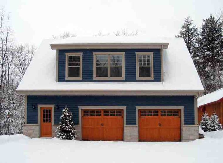 a blue house covered in snow with two garages and three windows on each side