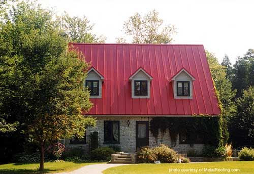 a red metal roof on a house in the middle of some trees and grass,