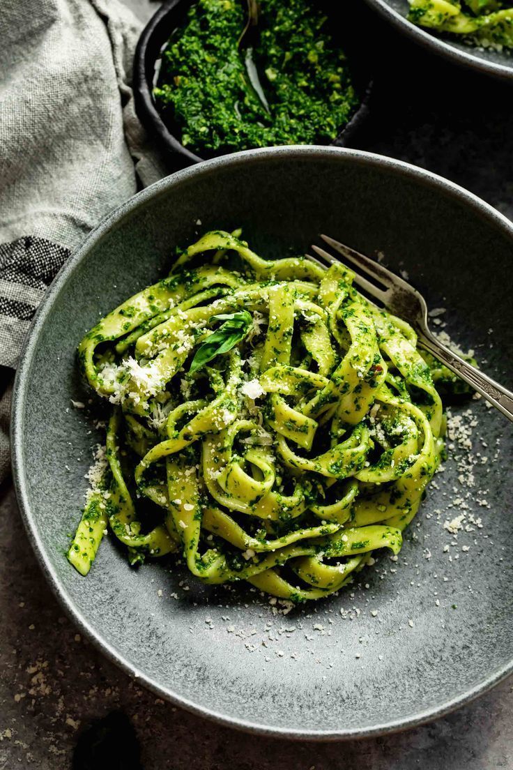 a bowl filled with pesto pasta and topped with parsley