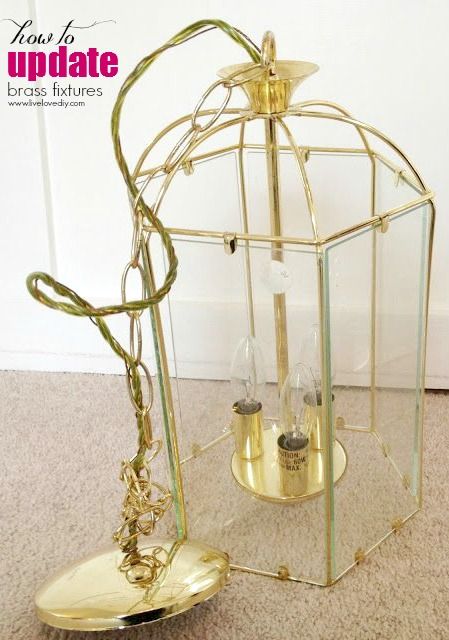 a golden birdcage sitting on the floor next to a candle holder