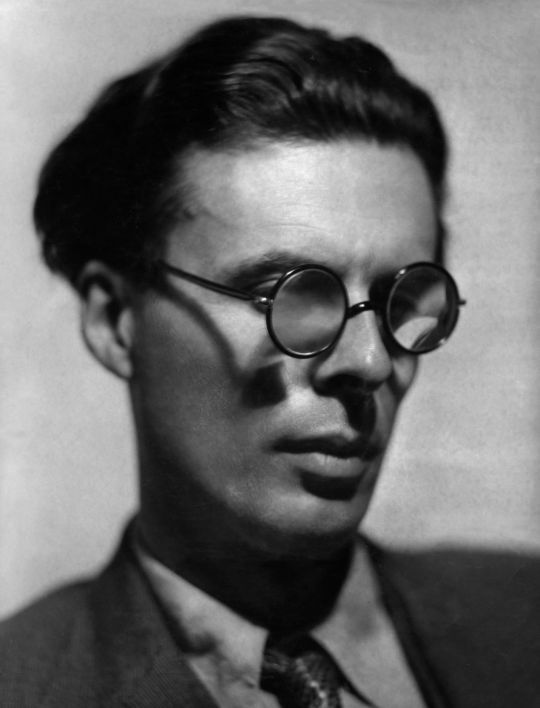 black and white photograph of a man in suit and tie with round glasses on his face