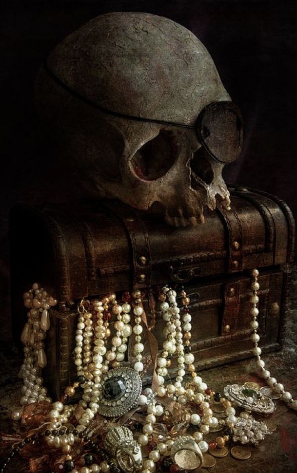 a skull sitting on top of a chest filled with jewelry