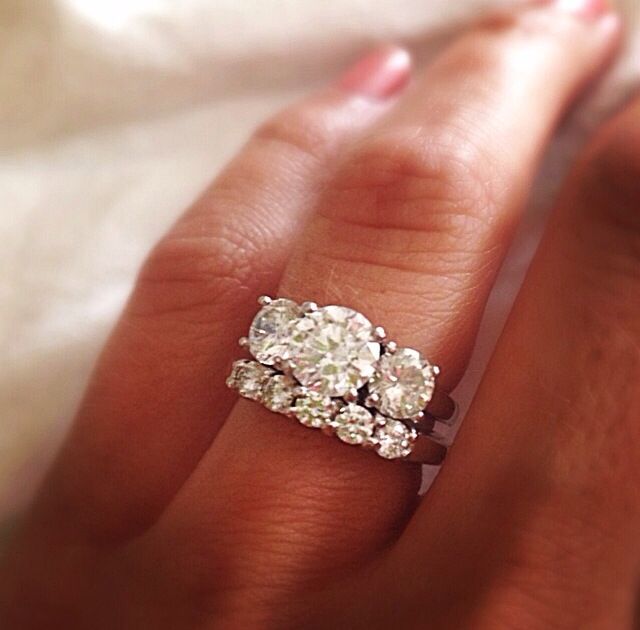 a woman's hand with two diamond rings on it and one ring is in the middle