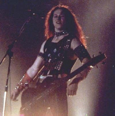 a woman with long hair playing an electric guitar in front of microphones on stage