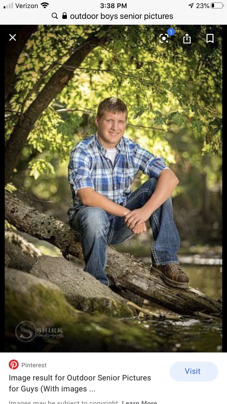 a man sitting on top of a tree branch next to a river