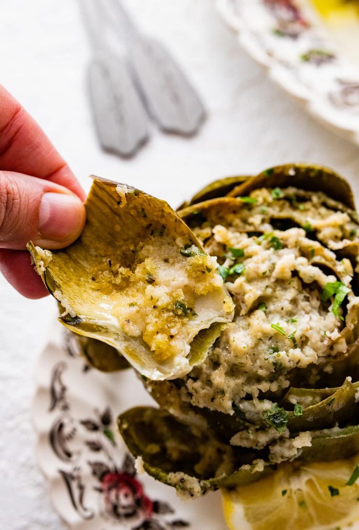 a hand holding a tortilla shell filled with artichokes and cheese