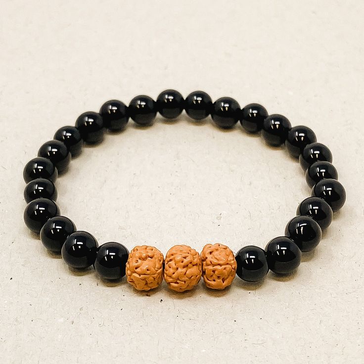 These bracelets are made using high-quality 6mm beads that come in three different sizes - Small (5inches-6inches), Medium (6inches-7inches), and Large (7inches-8inches) - to ensure a comfortable and secure fit on any wrist. Each bracelet features three Rudraksha Seed beads, which act as diffusers, releasing the essential oils into your skin as you wear them, providing the perfect dose of aromatherapy for relaxation during your busy schedule. Adjustable Black Beads Wristband, Adjustable Wristband With Black Round Beads, Adjustable Black Beads Bracelet For Meditation, Spiritual 8mm Beads Wristband, Spiritual Black Bracelet With Round Beads, Spiritual Black Wristband With Round Beads, Black Charm Bracelet With 8mm Beads, Black Charm Bracelet With 8mm Round Beads, Black 8mm Beads Bracelets For Meditation