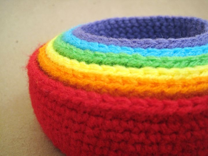 a multicolored crocheted basket sitting on top of a table