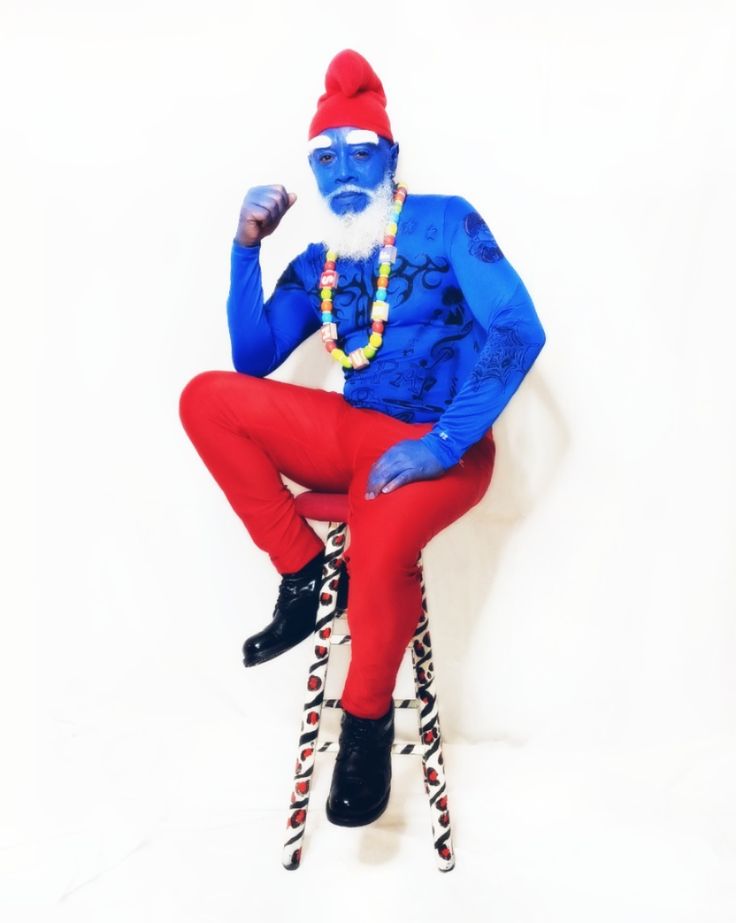 a man in blue and red is sitting on skis with his legs crossed while wearing black boots