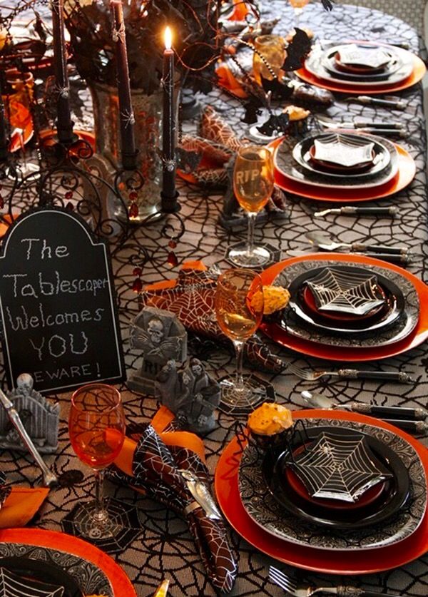 the table is set for halloween with black and orange plates