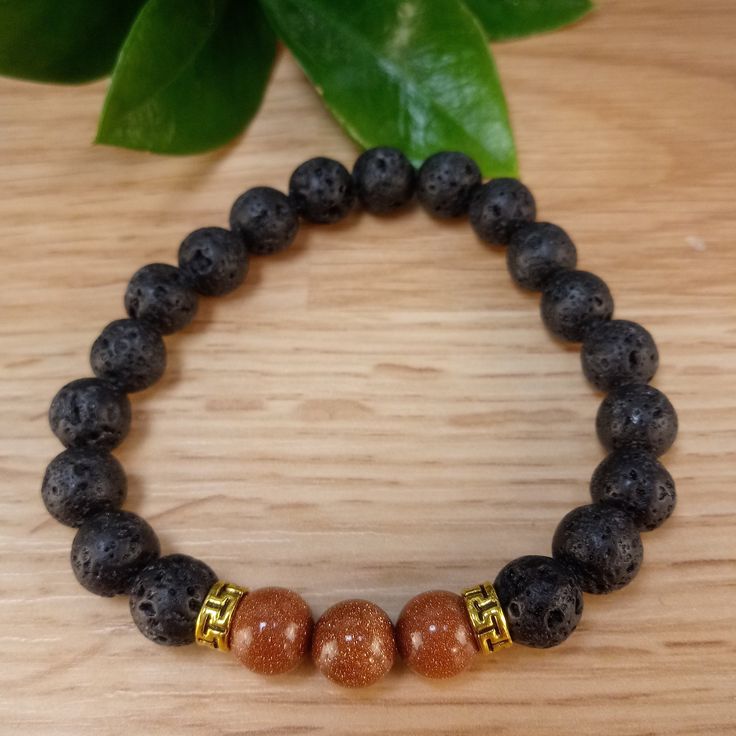 The bracelet contains two stones that are vital to our wellbeing: Goldstone and Lava Stone. The sparkles of Goldstone are symbolic of light that can always be found in the darkness. It deflects unwanted energies and is highly regarded in the spirit realm as a protective mineral. Lava Stone is a grounding stone that strengthens the connection to Mother Earth. A calming stone, it is instrumental in dissipating anger. It promotes positive changes where needed in behavioral issues. Our Brown Goldsto Lava Stone Bracelets With Natural Stones For Gift, Spiritual Lava Stone Stretch Bracelet Gift, Gift Bracelets With Natural Lava Stones, Adjustable Lava Stone Bracelet For Meditation, Adjustable Lava Stone Stretch Bracelet For Meditation, Spiritual Lava Stone Stretch Bracelet With Natural Stones, Meditation Bracelets With Natural Lava Stones, Spirit Realm, Positive Changes