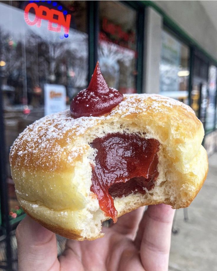 a person holding up a jelly filled doughnut