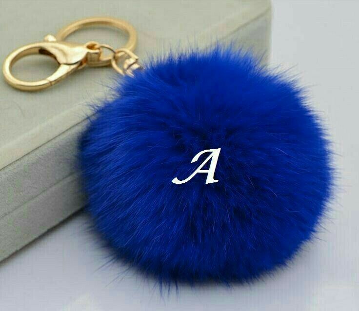 a blue fur ball keychain with the letter a on it