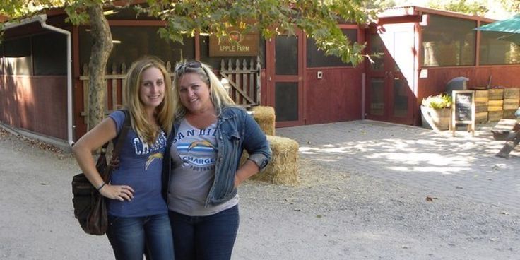 two women standing next to each other in front of a barn