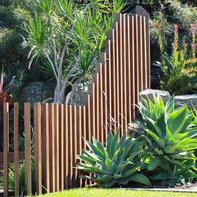 a wooden fence surrounded by plants and rocks