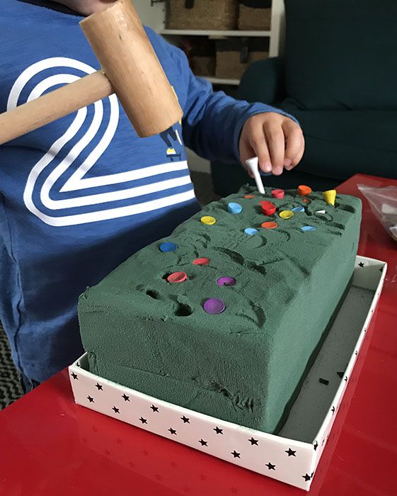 a young boy cutting into a cake with a baseball bat