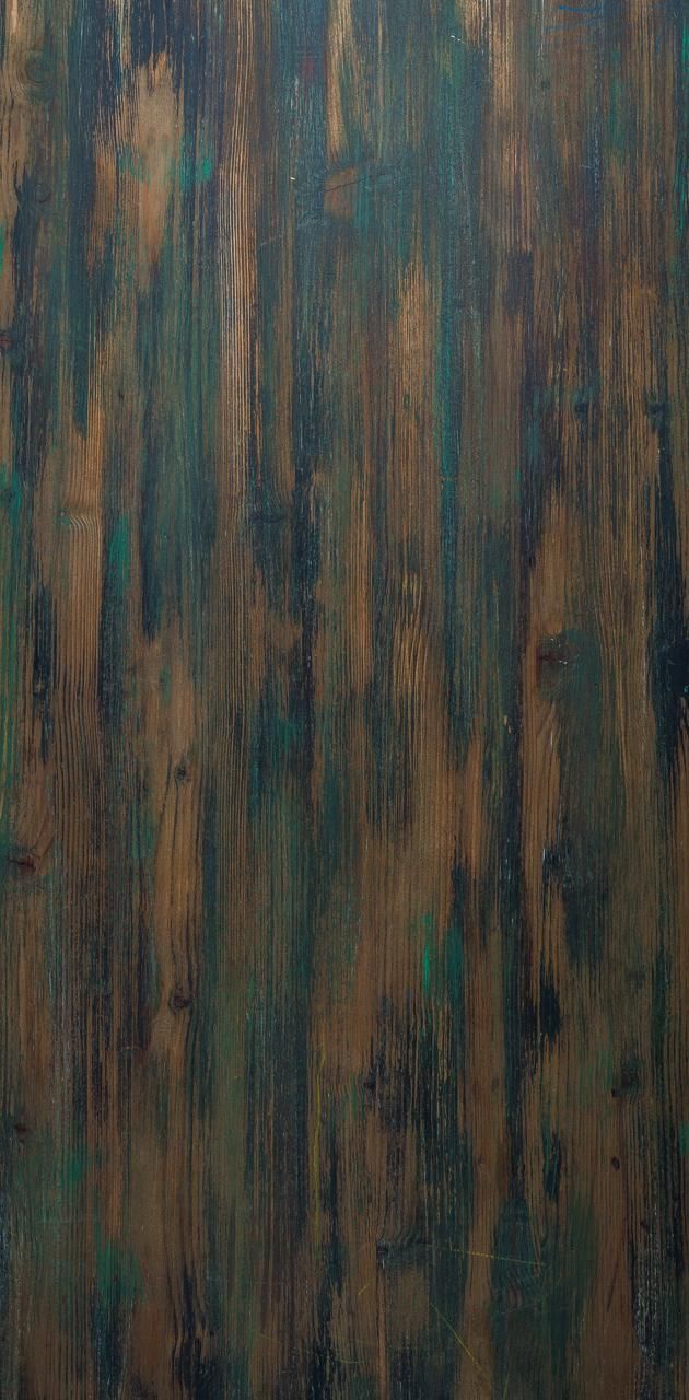 an old wooden wall with green paint on it's sides and brown wood planks