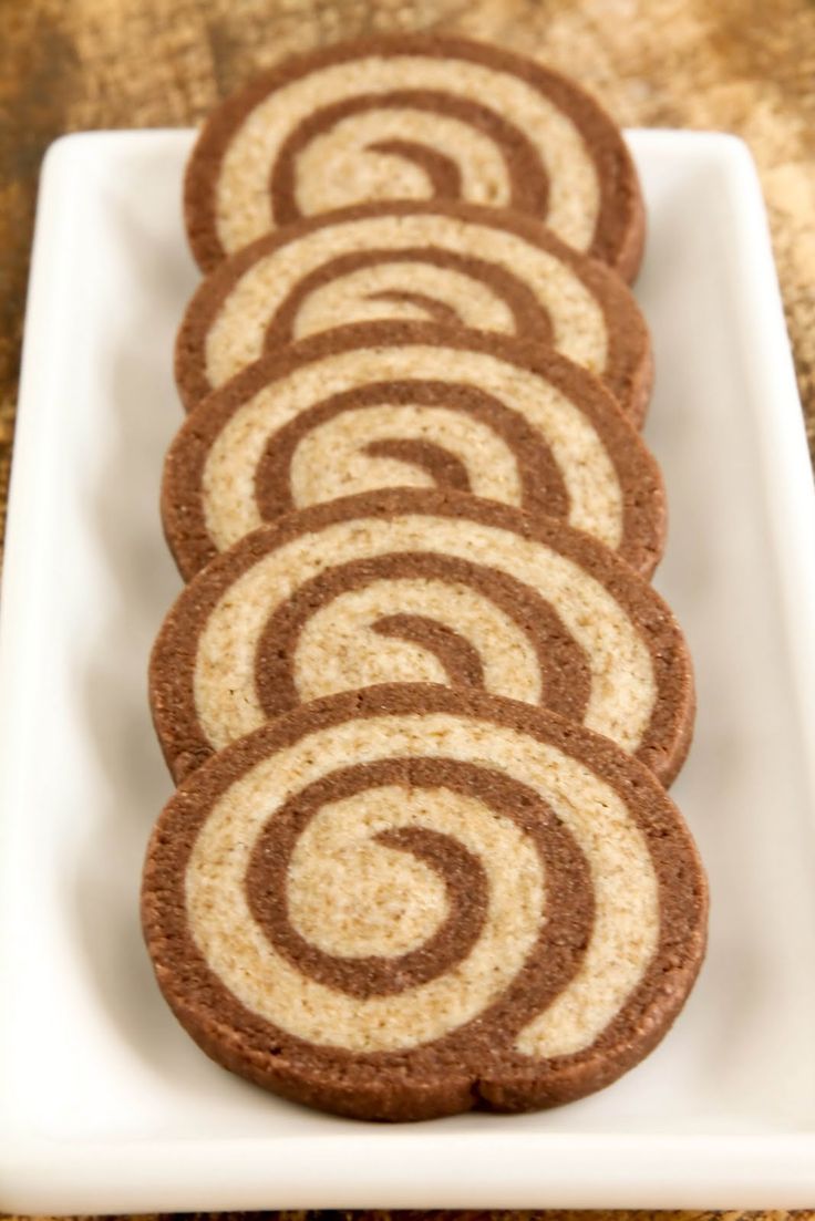 several cookies on a white plate with chocolate swirls in the middle and one cookie has been cut into smaller circles