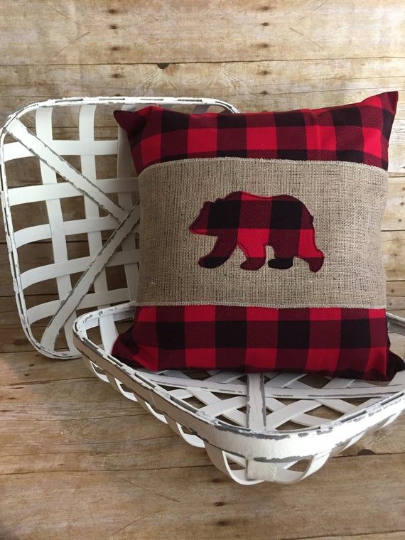 a red and black plaid bear pillow sitting on top of a white wicker basket