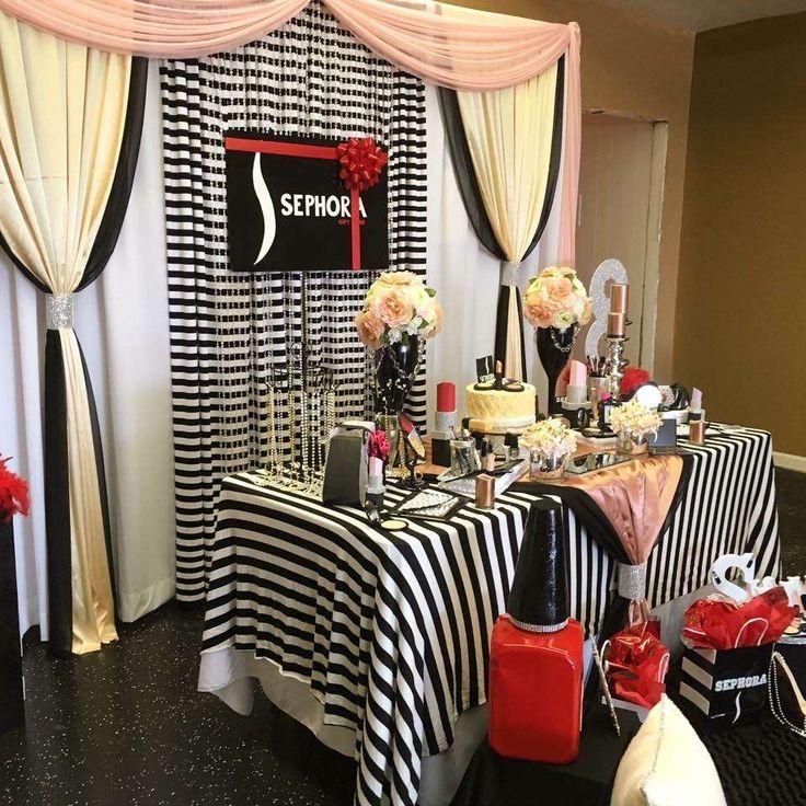 a black and white striped table cloth with red flowers on it is set up for an event