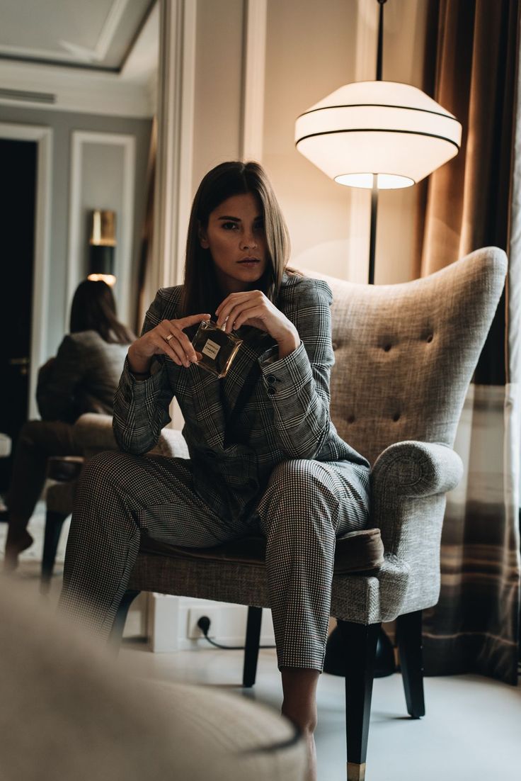 a woman sitting in a chair with her hand on her chest and looking at the camera