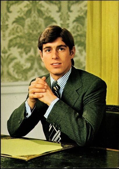 a man sitting at a desk with his hands folded in front of him, wearing a suit and tie