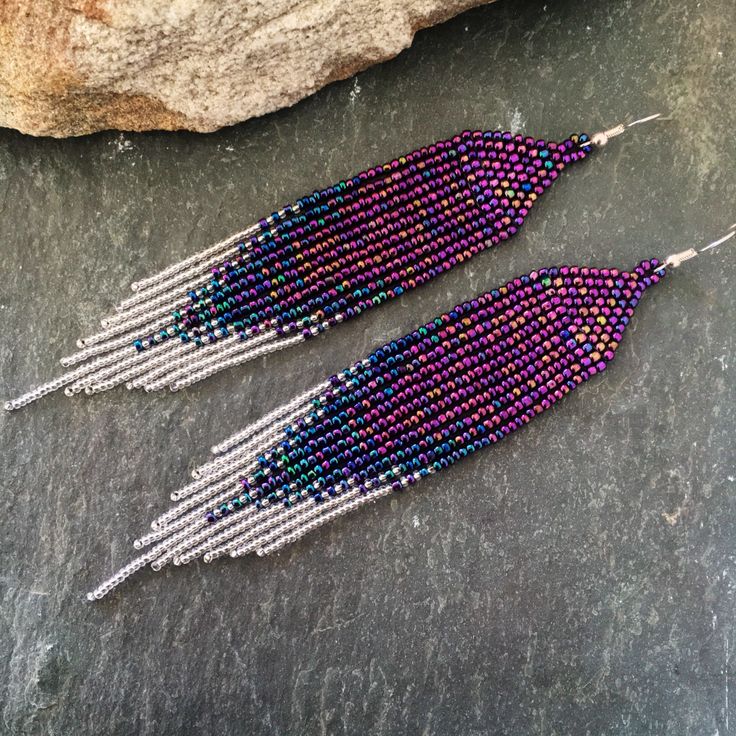 two pairs of beaded earrings sitting next to each other on top of a rock