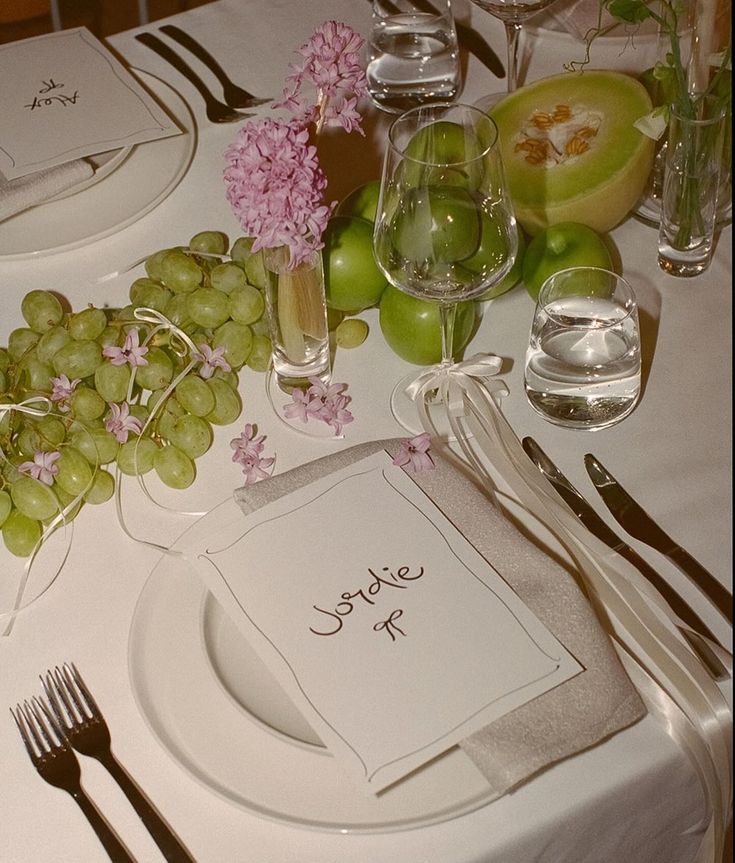 a table set with place settings, silverware and fruit for an elegant wedding reception