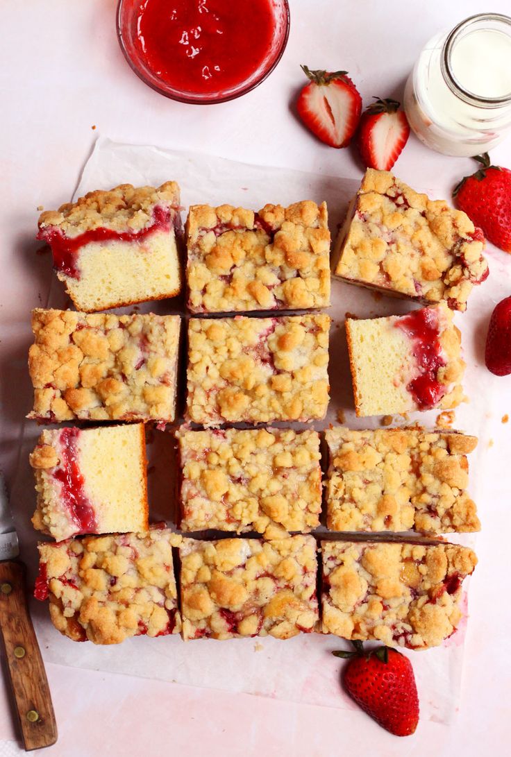 strawberry crumb bars cut into squares on a cutting board with strawberries next to them