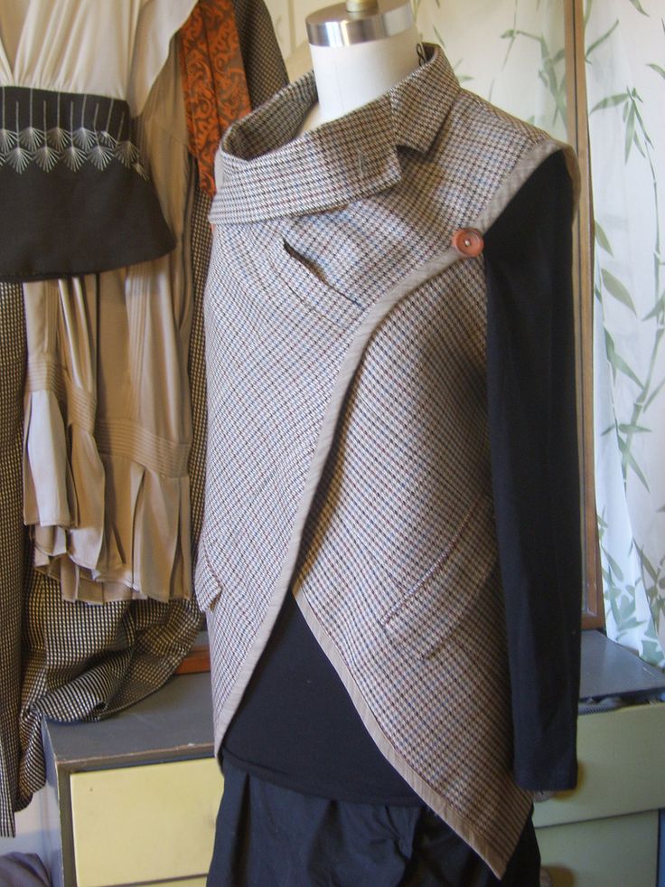 a mannequin wearing a jacket and tie on top of a wooden table next to clothes