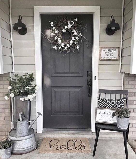 a front door with a welcome mat and two buckets on the steps next to it