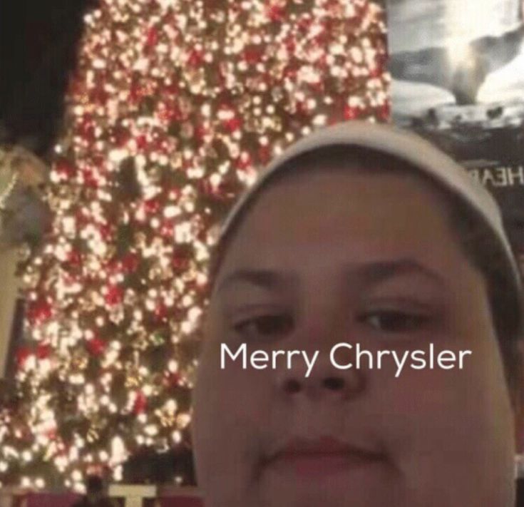 a man is standing in front of a christmas tree with the words merry chrysler on it