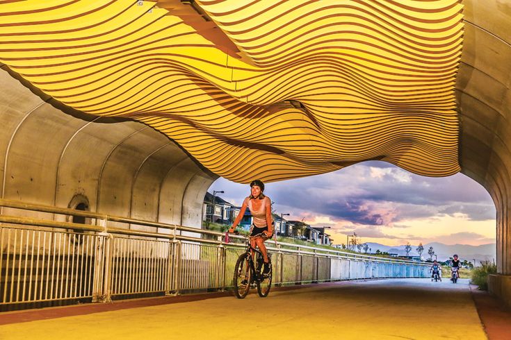 a man riding a bike under a bridge with wavy designs on it's side