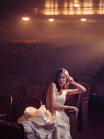 a woman is sitting in an empty theater