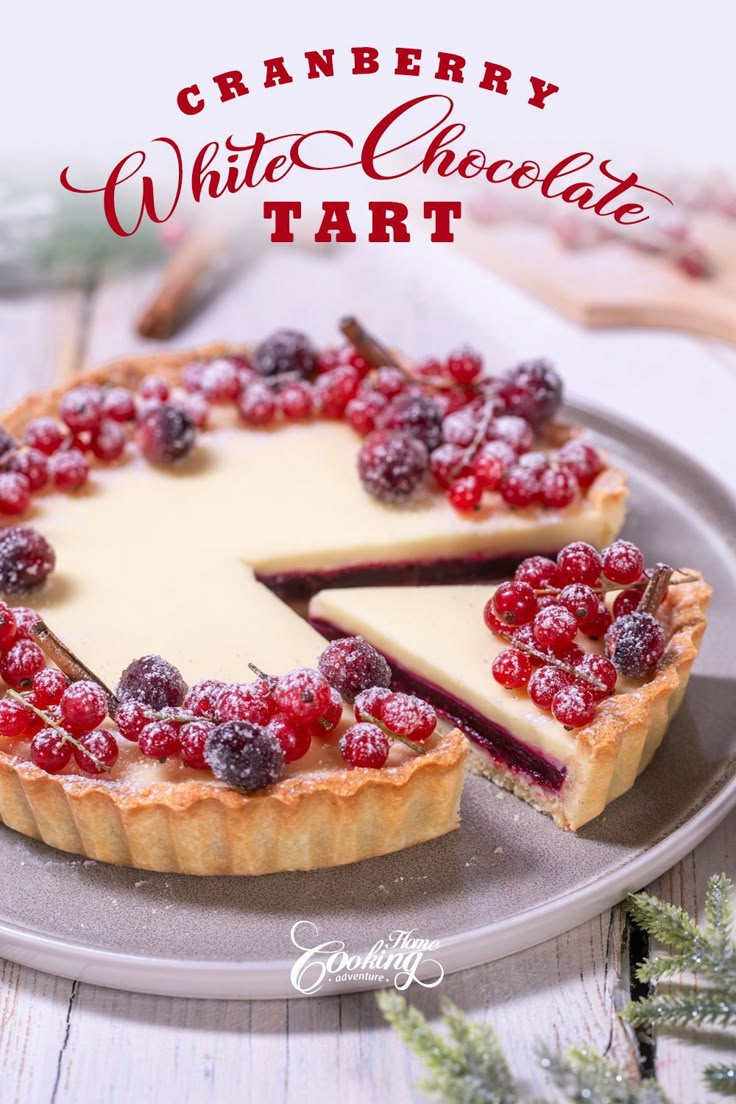 a white chocolate tart topped with berries and cranberries on a silver plate