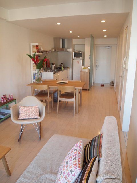 a living room filled with furniture next to a dining room table and chairs on top of a hard wood floor