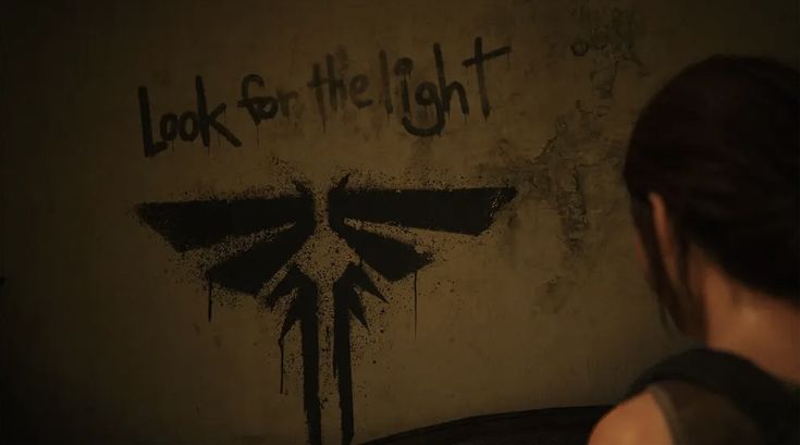 a woman standing in front of a wall with the words look for the light painted on it