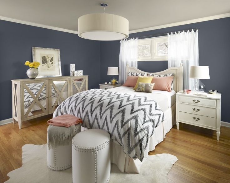 a bedroom with blue walls, white furniture and wooden floors is pictured in this image