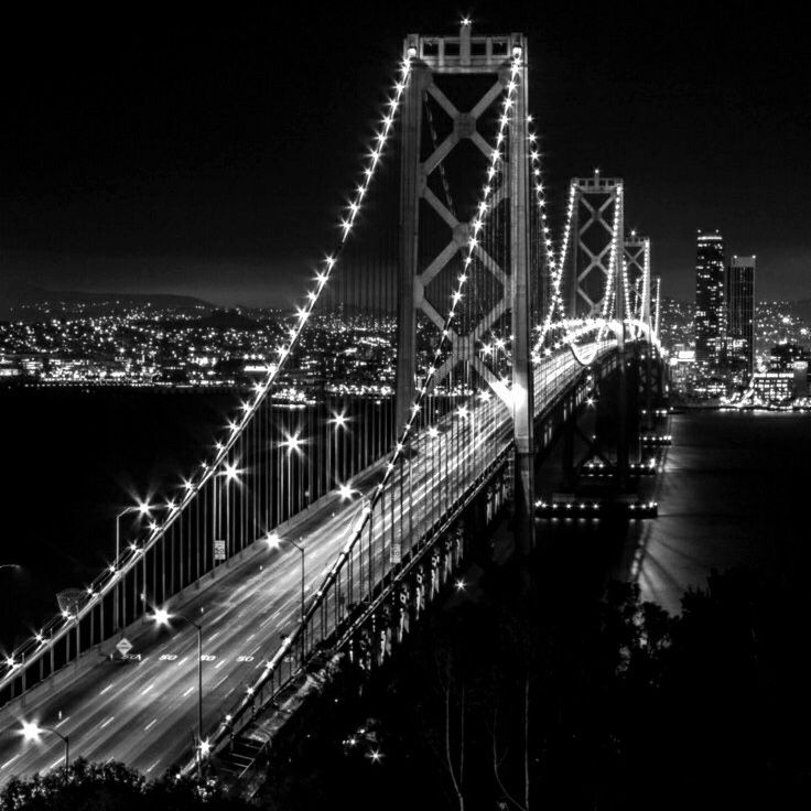 black and white photograph of the bay bridge in san francisco at night with lights on