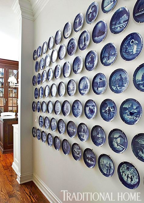 a wall full of blue and white plates mounted to the side of a wall next to a wooden floor