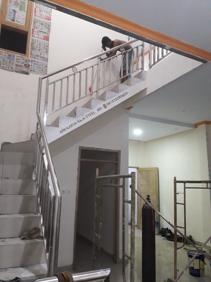 a man standing on top of a stair case next to a metal hand rail in a building