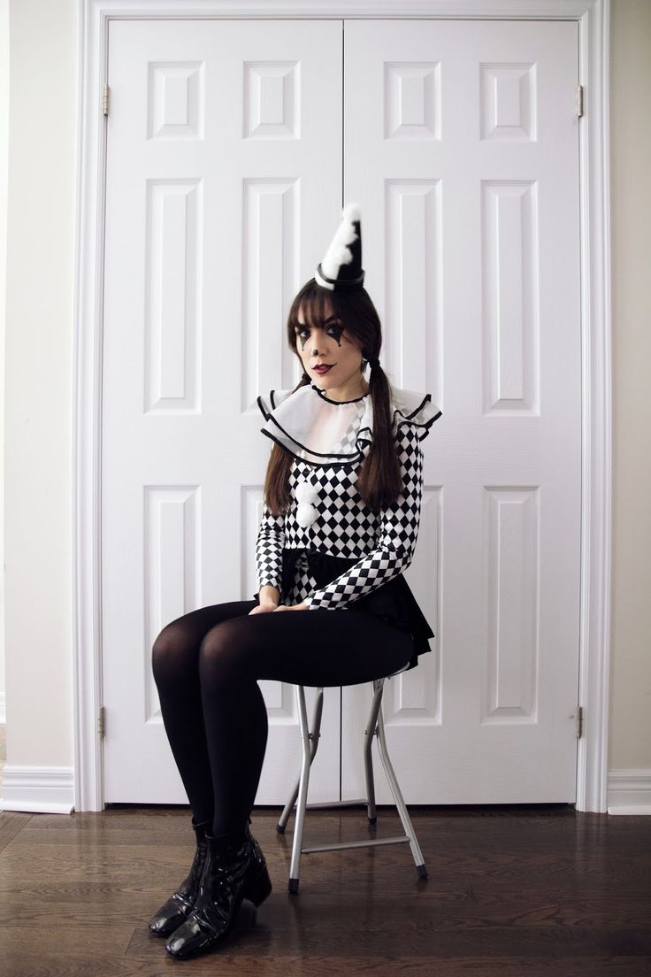 a woman sitting on top of a chair in front of a white door wearing a black and white dress